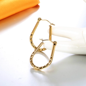 Detailed macro view of 18K gold-plated U-shaped earrings with hammered metal texture