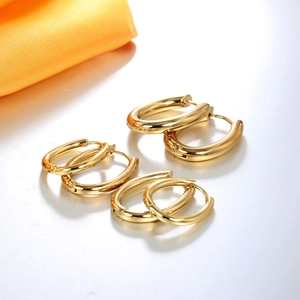 Three pairs of polished gold hoop earrings in various sizes on a white surface