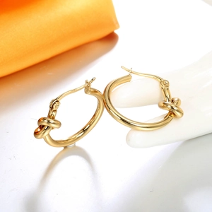 Boucles d'oreilles créoles nouées en acier titane plaqué or 18 carats sur un modèle