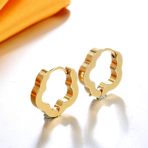 Boucles d'oreilles créoles hexagonales dorées polies sur surface blanche brillante