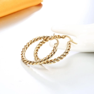 Elegant gold-plated twisted rope hoop earrings displayed on a white ceramic hand stand