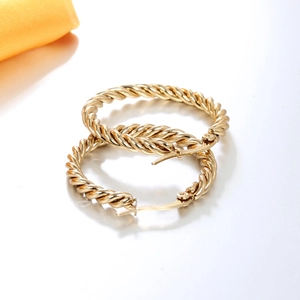 Elegant gold twisted rope hoop earrings with a textured spiral design on a white background