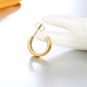 Detailed view of C-shaped 18K gold plated hoop earrings on white ceramic display