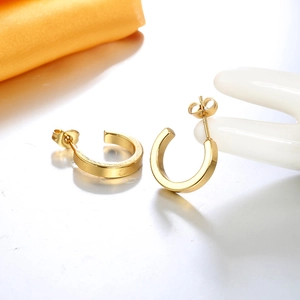 Detail of 18K gold plated C-shaped hoop earrings displayed on a white ceramic hand prop