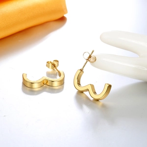 Macro detail of wave-shaped geometric earrings with 18K gold-plated polished mirror finish