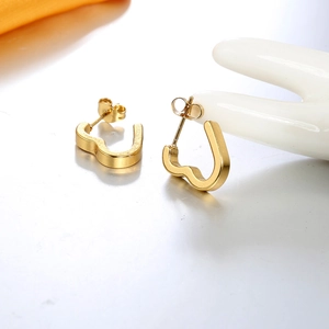 Detail shot of heart-shaped gold-plated stud earrings on a ceramic jewelry stand