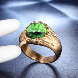 Nahaufnahme eines goldfarbenen Titanrings für Herren mit grünem Auge und geprägter Textur