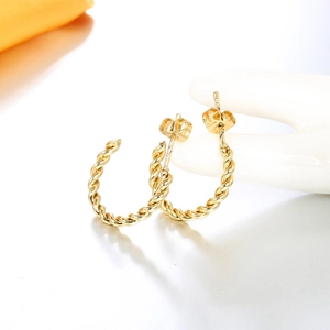 Elegante goldene gedrehte C-förmige Creolen am Handmodell für einen stilvollen Alltagslook
