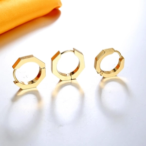 Detailed view of three gold hexagonal stainless steel huggie earrings on white reflective surface