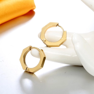 Detail view of gold matte hexagonal hoop earrings displayed on a white ceramic hand model