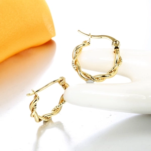 Nahaufnahme goldener gedrehter Creolen mit minimalistischer geometrischer Metalltextur