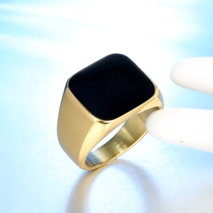 Dettaglio macro di anello a sigillo da uomo dorato con intarsio nero e acciaio spazzolato