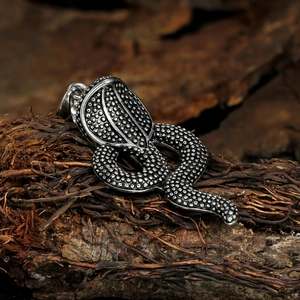 Retro stainless steel cobra snake pendant with textured scales on rustic bark background