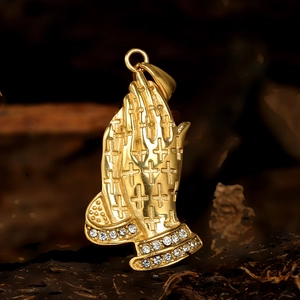 Vue macro d'un pendentif mains en prière doré avec texture croix et strass