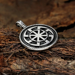 Detailed shot of retro silver Viking Kolovrat sun wheel pendant on a textured dark wood background