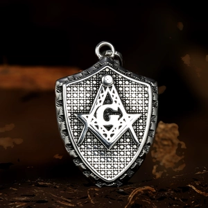 Macro view of a shield-shaped stainless steel pendant with Masonic compass and square