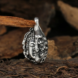 Macro detail of retro Buddha and Demon pendant with antique finish on dark wood roots