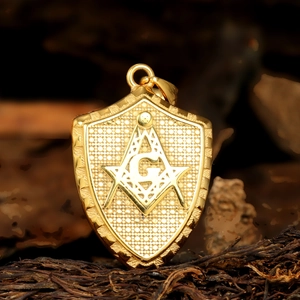 Detailed close-up of shield-shaped gold Freemason pendant with compass and G symbol