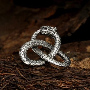 Intricate double snake pendant in silver metal on rustic bark background for a mystic look