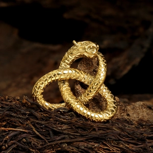 Mythical twin snake pendant with golden scales on a rustic vintage wood background