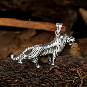 Détail du pendentif tigre en acier inoxydable avec textures rayées sur fond de bois sombre
