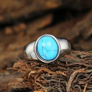 Vintage stainless steel ring featuring an oval turquoise stone on rustic wood background