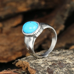 Vintage stainless steel ring with round turquoise gemstone on natural wood bark background
