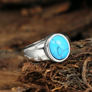 Retro stainless steel ring with oval turquoise stone on a natural wood background
