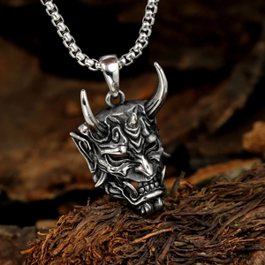 Close-up of retro silver stainless steel Hannya mask pendant with weathered dark finish