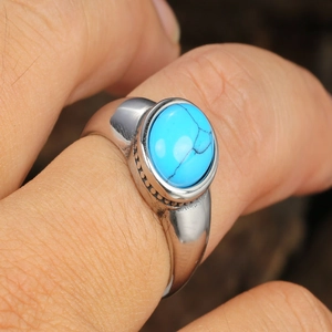 Close-up of men's stainless steel ring featuring an oval turquoise with black veins