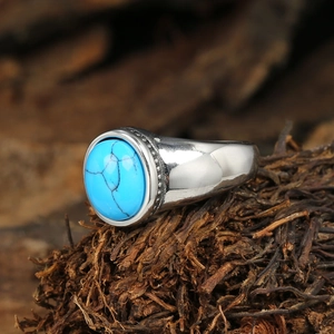 Close-up of bohemian silver ring with oval turquoise stone on natural wooden background