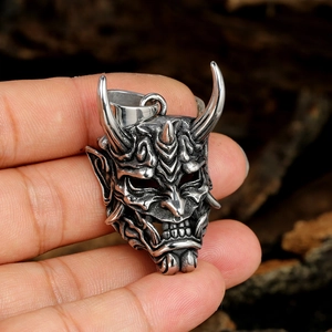 Macro shot of retro stainless steel devil mask pendant with textured horns and vintage finish