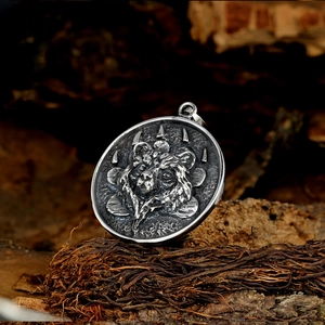 Macro detail of silver lion head pendant with embossed bear paw on rustic wood background