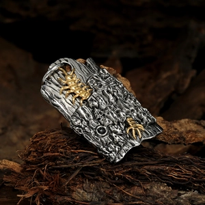 Macro detail of bionic metal pendant with centipede motif and black gemstone on wood
