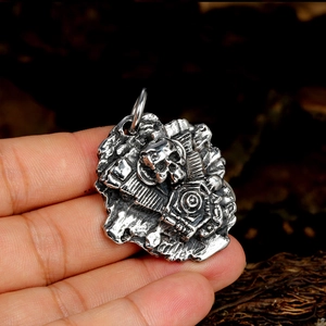 Detailed macro view of a silver punk mechanical skull pendant held in hand for scale