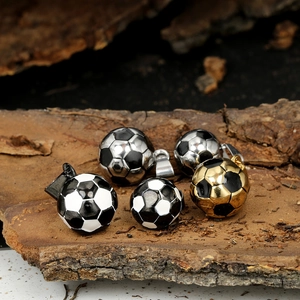 Détails de pendentifs de football en or et argent posés sur une écorce rustique