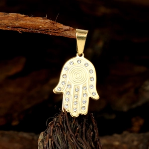 Golden Hamsa Hand pendant with rhinestones and textured details on dark wood