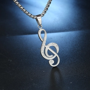 Gros plan du pendentif clé de sol en argent avec cristaux sur une chaîne maille vénitienne