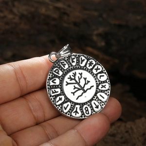 Nordic tree of life stainless steel pendant with viking runes on textured wood