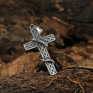 Pendentif croix rétro en acier inoxydable avec serpent détaillé sur un fond texturé naturel