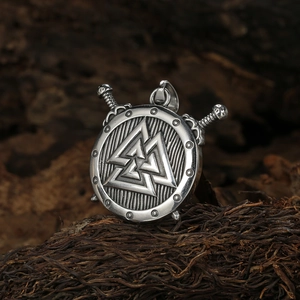 Pendentif amulette viking avec bouclier et épées sur fond de bois rustique