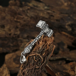 Viking Thor's Hammer Mjölnir pendant in stainless steel with Valknut symbols on dark wood