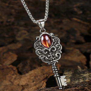 Collier clé vintage punk avec pierre grenat et motifs gravés sur fond bois sombre
