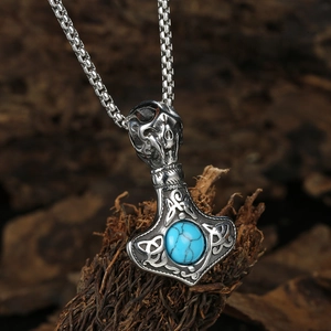 Detailed macro view of a vintage Mjölnir pendant with skull and turquoise stone inlay