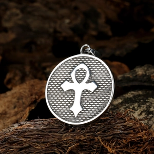 Macro shot of silver Eye of Horus pendant on wood background with Ankh symbol details