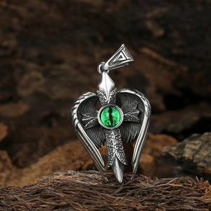 Vue macro du pendentif gothique avec ailes, croix et oeil vert sur bois rustique
