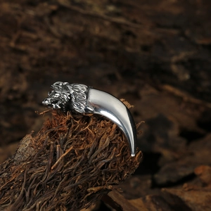 Pendentif tête de loup et dent en acier inoxydable sur fond de bois sombre