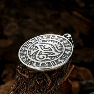 Vintage stainless steel Eye of Horus pendant with Egyptian hieroglyphs on wood background