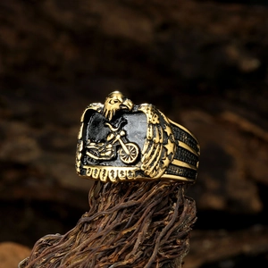 Close-up of vintage steel biker ring with gold eagle and motorcycle relief on bark