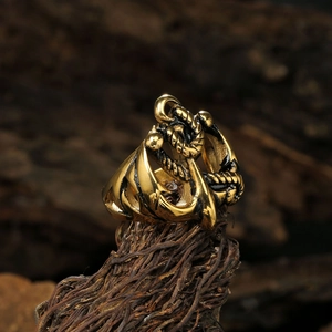 Vintage gold stainless steel nautical anchor ring displayed on rustic tree bark